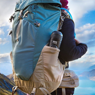 A travel coffee maker mounted to a hiking backpack