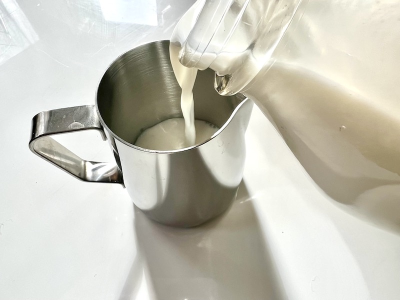pouring milk into latte art steaming pitcher