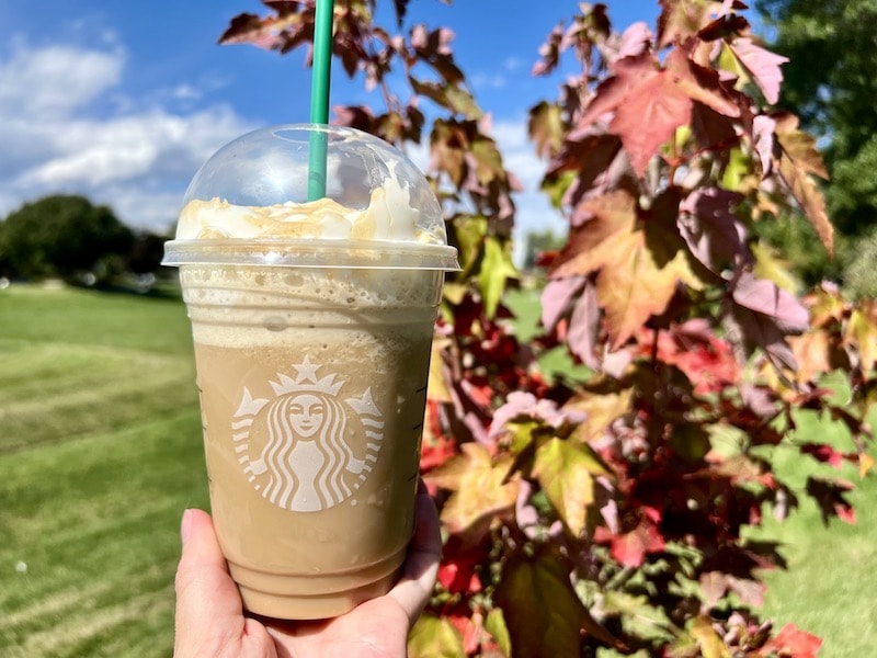 Starbucks apple crisp oatmilk frappuccino in front of fall leaves