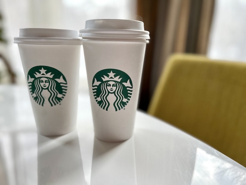 two starbucks hot drinks in paper cups by office chair_kate